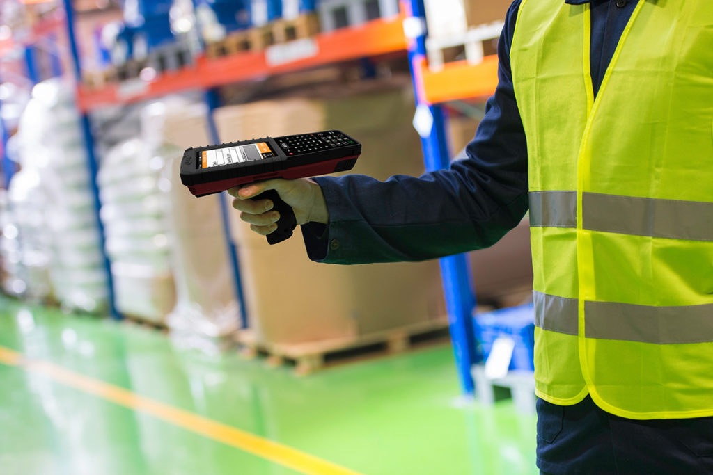 A warehouse working using a striker handheld kiosk while at work.