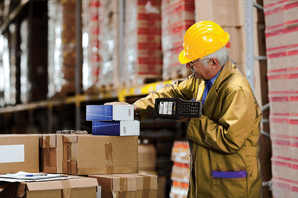 An elder man scanning product barcodes in a warehouse.